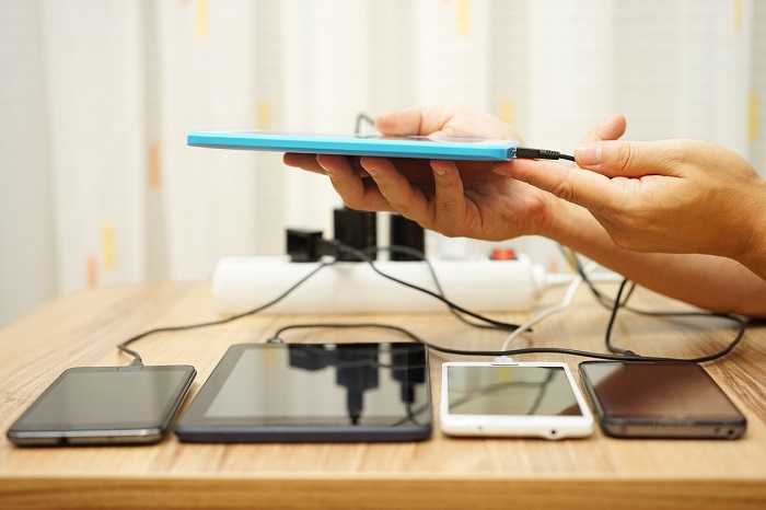 Person charging 4 tablets and putting the 5th one on charge